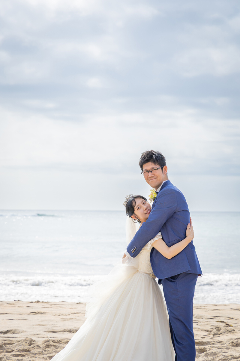 波打ち際で新郎様にそっと抱きつく新婦様