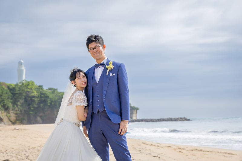 灯台と海をバックに寄り添う爽やかなふたり
