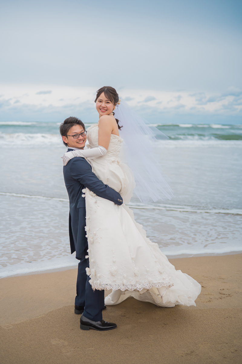 砂浜で新婦様を軽やかに抱き上げるポーズ