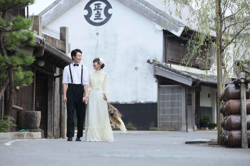 歴史ある酒蔵跡を背景に、寄り添って歩くおふたり。