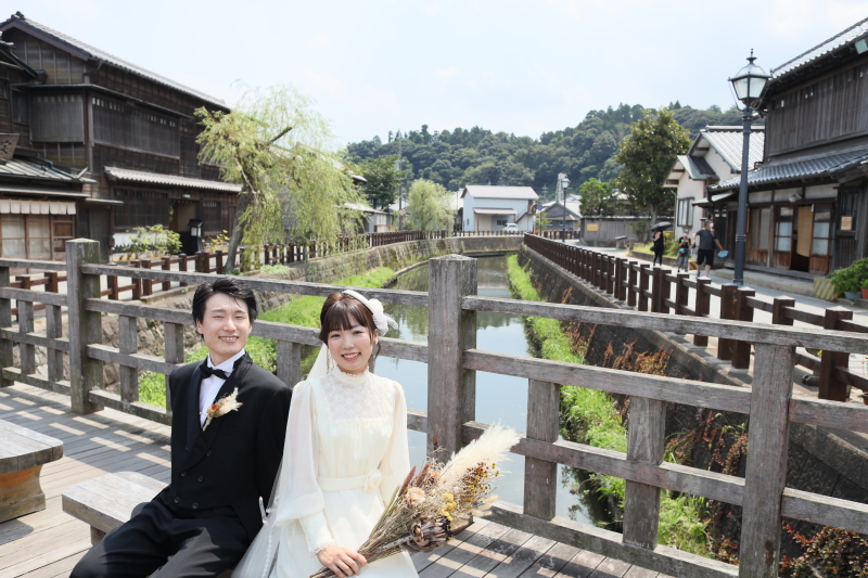 川沿いの橋の上で微笑むふたり。