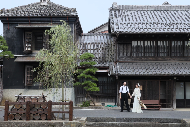 蔵造りの建物を背景に、手を取り合うふたり。