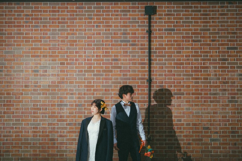 レンガ作りの壁の前でスタイリッシュに