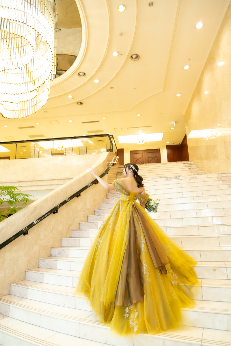 白亜の大階段に映える、ゴールドドレスの余韻。