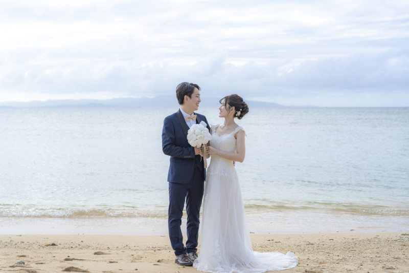 青空の下、手を取り合って見つめ合うおふたり