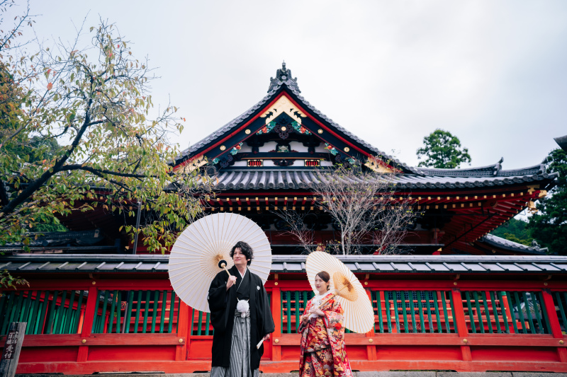 朱の社で並ぶ、静かな和装のふたり