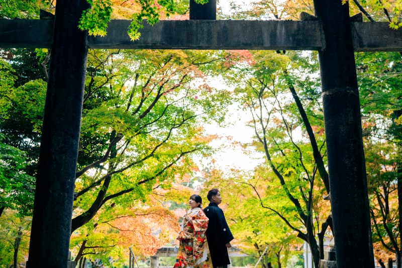 鳥居と紅葉に囲まれた和装の背中合わせショット