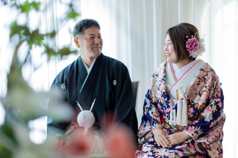手前の花越しに視線を交わすやさしい表情のお二人