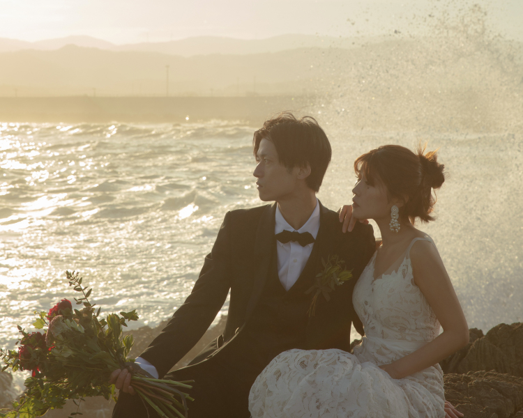 夕暮れの光が新郎新婦に差し込み2人のシルエットが浮き立ったところに後ろから波が岩場に跳ね返る瞬間を狙って撮影しました。ご確認お願い致します。