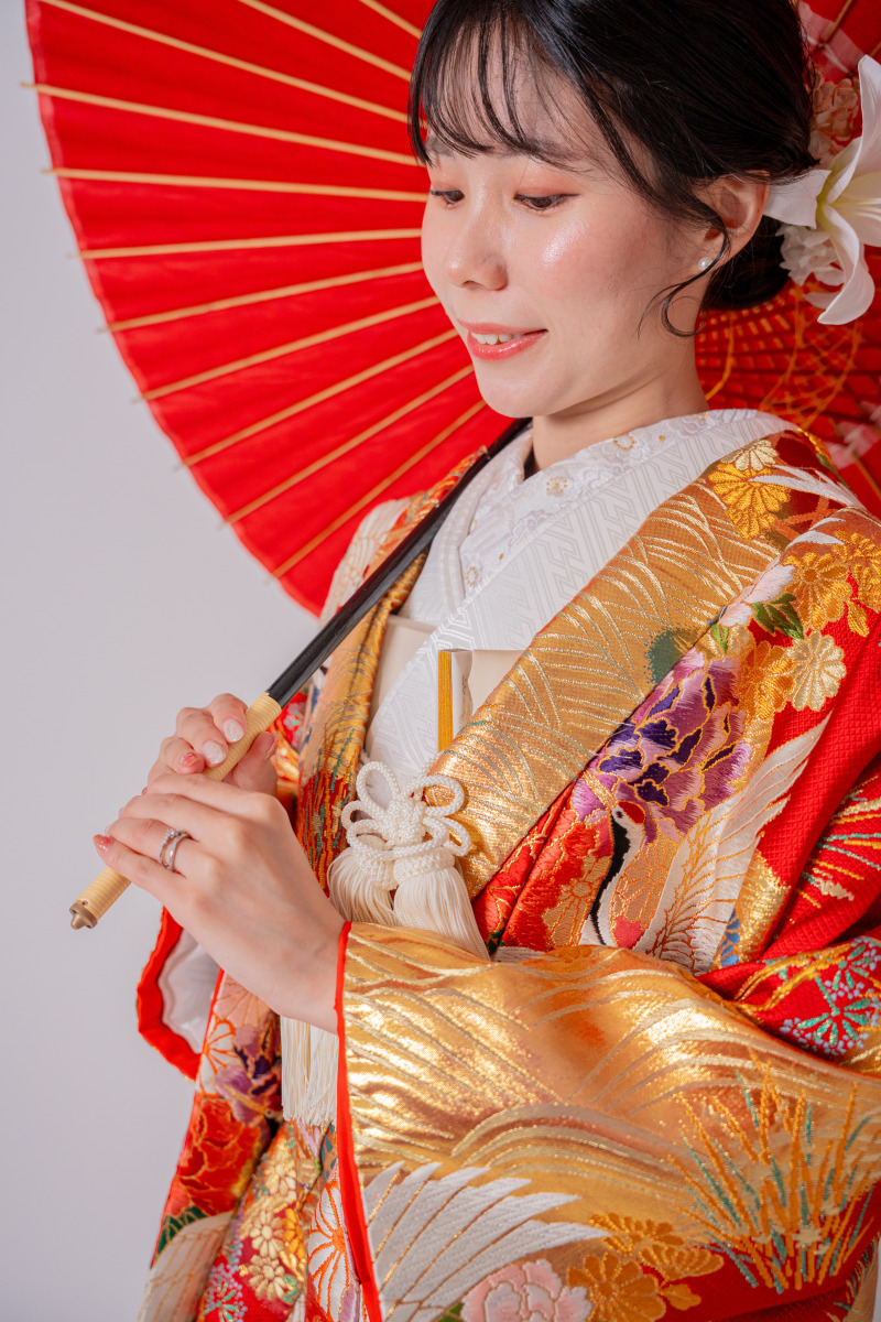 朱色の和傘に重ねた手元と控えめな笑顔