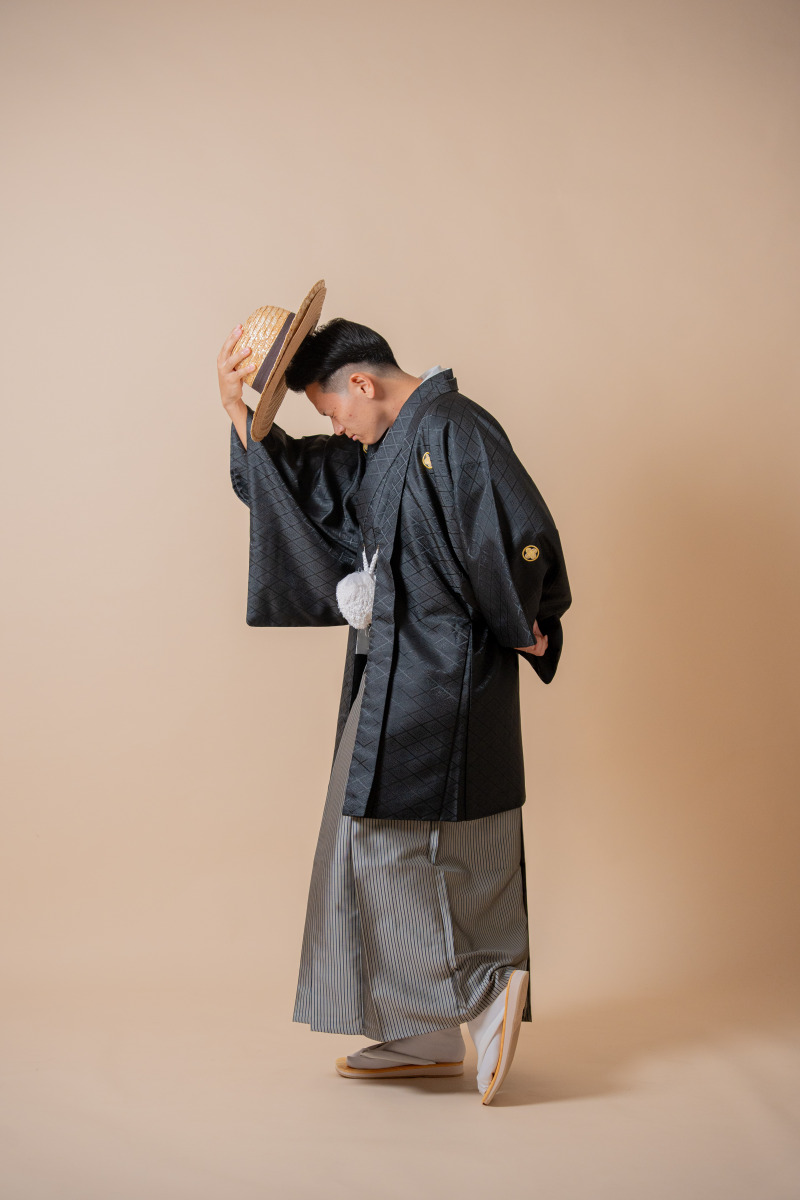 麦わら帽子を手にクールなポーズを決めて