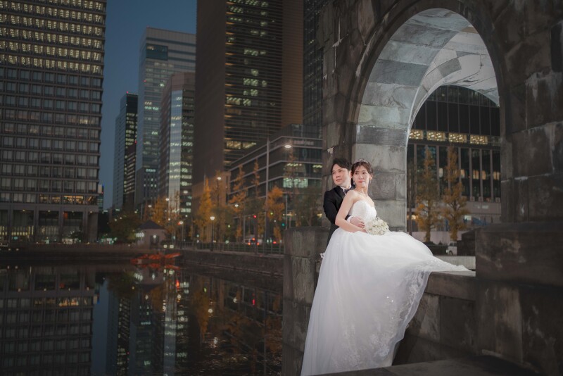 ライトアップされた建物を背景にした一枚。日の入り直後の時間帯を活かし、夜に切り替わる前のノスタルジックな空気感とともに、おふたりの姿を美しく収めました。